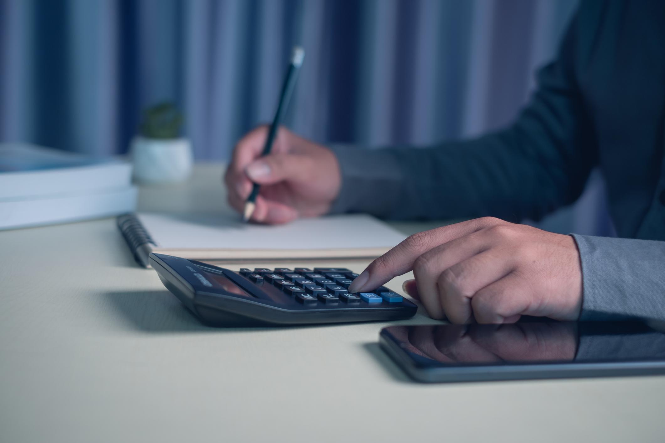 person calculating monthly expenses for 50/30/20 budget rule